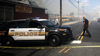 Paterson officer walks behind police tape.