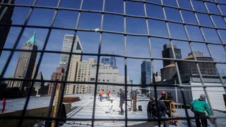 Construction workers update the roofing on a high rise at 160 Water Street in Manhattan's financial district, for the building's conversion to residential apartments, Tuesday, April 11, 2023, in New York.