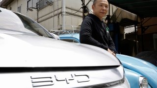 Osamu Furukawa stands next to his new BYD ATTO 3 electric car, that’s parked besides a Volkswagen converted into an EV, in Yokohama, south of Tokyo, Tuesday, April 25, 2023. BYD Auto is part of a wave of Chinese electric car exporters that are starting to compete with Western and Japanese brands in their home markets. They bring fast-developing technology and low prices that Tesla Inc.’s chief financial officer says “are scary.” (AP Photo/Yuri Kageyama)