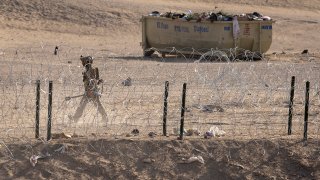 Texas National Guard soldier walks through an emptied-out migrant camp at the U.S.-Mexico border on May 13, 2023 to El Paso, Texas. After a big surge the week before, the number of new immigrant arrivals has dropped since the end of the U.S. Title 42 immigration policy.