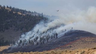 Helicopter crew battles wildfire burning in forest and rangeland, August 2022, in northwestern Montana not far west of the Flathead Lake area southwest of Kalispell.