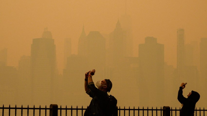 People take photos of the sun in Central Park as smoke from wildfires in Canada causes hazy conditions in New York City, June 7, 2023.