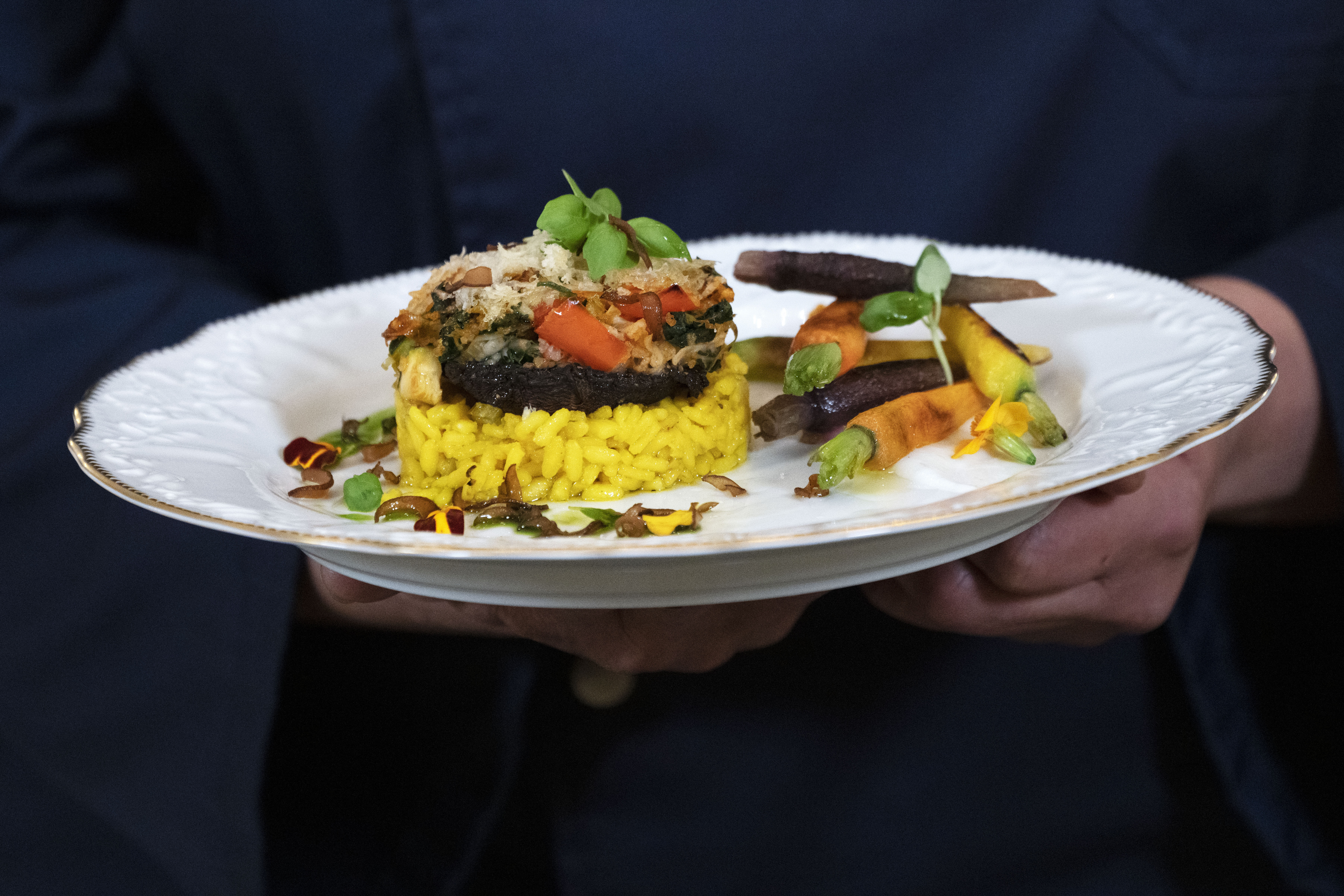 A chef holds the main course, stuffed portobello mushrooms with a creamy saffron-infused risotto, that will be served at Thursday evening's State Dinner with India, during a media preview, Wednesday, June 21, 2023, at the White House in Washington. 