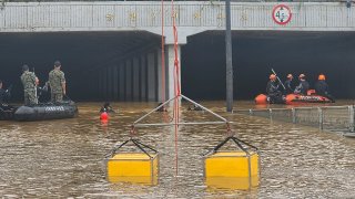 In this photo provided by South Korea National Fire Agency, rescuers search for survivors along a road submerged by floodwaters leading to an underground tunnel in Cheongju, South Korea, Sunday, July 16, 2023. Days of heavy rain triggered flash floods and landslides and destroyed homes, leaving scores of people dead and forcing thousands to evacuate, officials said Sunday.(South Korea National Fire Agency via AP)