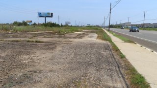 A car drives past a vacant lot, Wednesday, July 27, 2023, in Egg Harbor Township, N.J., where a string of seedy motels used to stand. The discovery of four dead women in a drainage ditch behind the motels just outside Atlantic City was shocking news in 2006.