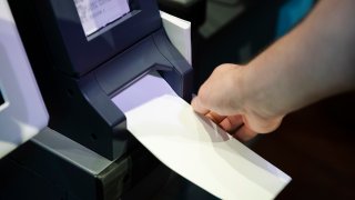FILE—In this June 13, 2019, file photo, an investigator with the Office of the City Commissioners, demonstrates the ExpressVote XL voting machine at the Reading Terminal Market in Philadelphia.