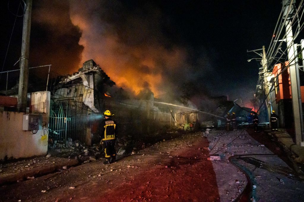 Firefighters work to extinguish a fire after an explosion in a commercial establishment in San Cristobal, Dominican Republic, on August 14, 2023. 