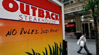 An Outback Steakhouse truck sits parked outside a restaurant in New York.