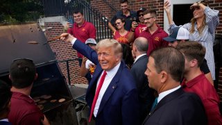 Former President Donald Trump holds a spatula with a hamburger