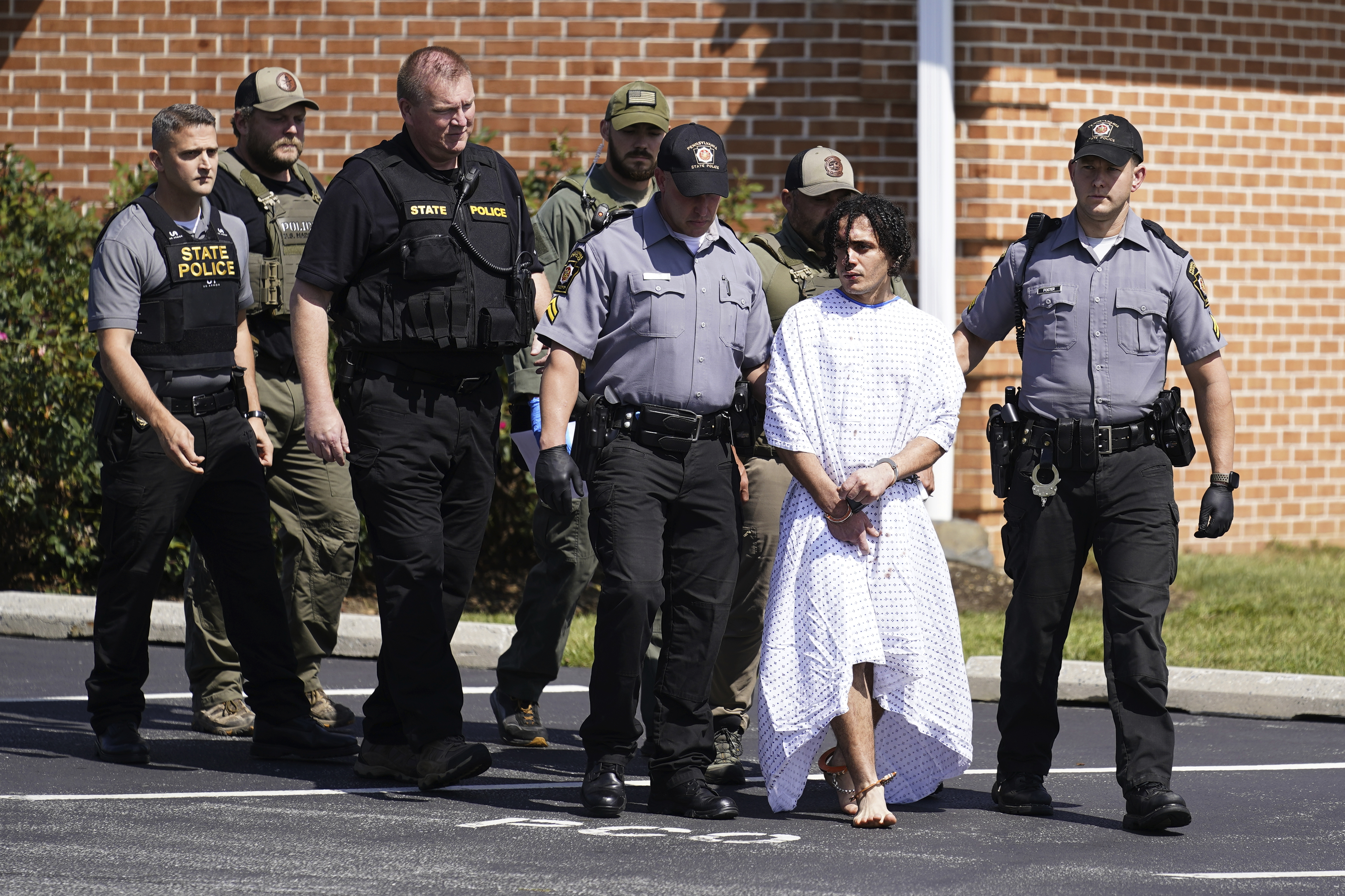 Danelo Cavalcante in a gown led by police after his arrest.