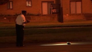A Philadelphia police officer shines a flashlight on a shoe left in the roadway after a man was killed in a hit-and-run on Roosevelt Boulevard early Monday.