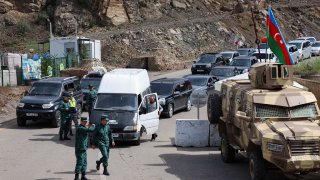 Azerbaijan soldiers regulate traffic as refugees wait in their cars to leave Karabakh for Armenia, at the in Lachin border, on Sept. 26, 2023.