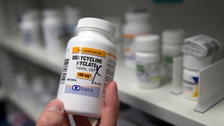 FILE - A pharmacist holds a bottle of the antibiotic doxycycline hyclate in Sacramento, Calif., July 8, 2016.