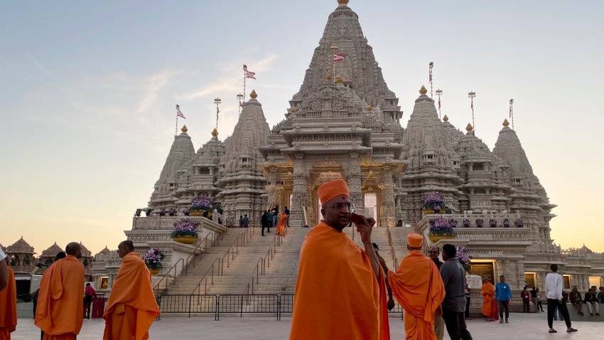 Monks in saffron robes walk in front of the BAPS Swaminarayan Akshardham, the largest Hindu temple outside India in the modern era, on Wednesday Oct. 4, 2023, in Robbinsville, N.J. The temple was partly built using marble from Italy and limestone from Bulgaria hand-carved by artisans in India and shipped to New Jersey. (AP Photo/Luis Andres Henao)