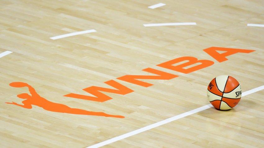 A basketball sits near the WNBA logo.