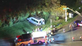 A van is crashed into the trees off the road as first responders work a crash scene in Bucks County