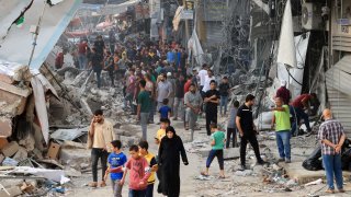 Palestinians walking amid the rubble of destroyed and damaged building in the heavily bombarded city center of Khan Yunis in the southern Gaza Strip on October 10, 2023.