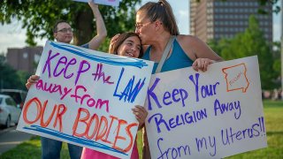 FILE - A mother and daughter attend a protest opposing the Supreme Court ruling overturning federal protections for abortion rights, June 24, 2022, in Kansas City, Mo.