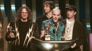 FILE – Michael Stipe, of the band R.E.M., center, speaks as he accepts the Video Vanguard award during the 1995 MTV Video Music Awards at Radio City Music Hall in New York on Sept. 7, 1995. Standing by are fellow band members, from left, Mike Mills, Peter buck and Bill Berry.