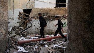 Palestinians walk by a damaged building