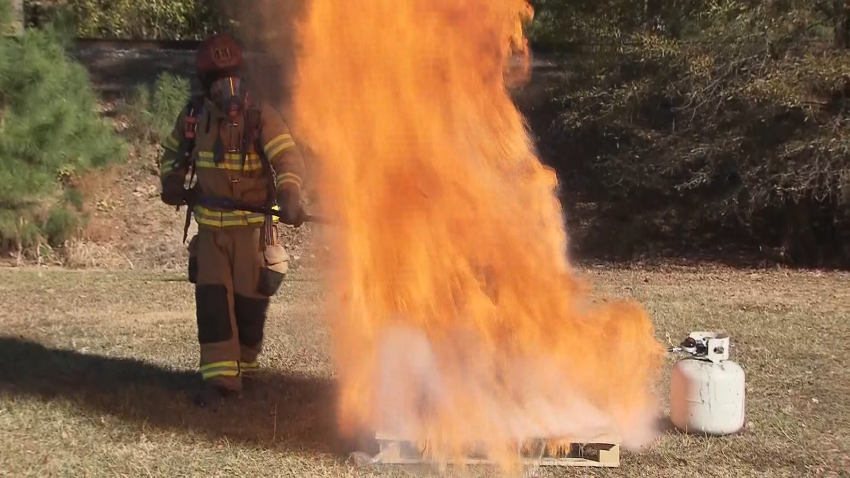 Firefighter standing next to a fire demonstration.