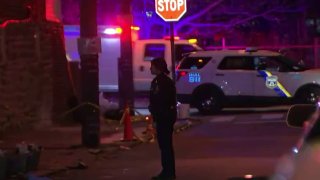 An officer investigates after two men died in a shootout in Juniata Park on Saturday night.