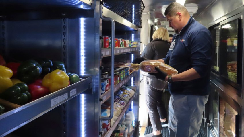 A worker adds bread to shelves of a specially modified bus that serves as a mobile supermarket in Atlantic City N.J. on Friday, Dec. 8, 2023. Virtua Health and the New Jersey Economic Development Authority are operating a service to bring fresh groceries and produce to Atlantic City, where plans for what would be the city's first supermarket in nearly 20 years recently fell through. (AP Photo/Wayne Parry)