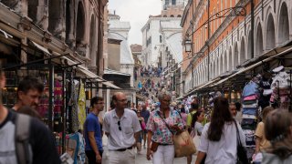 Tourists walk in a crowded street in Venice