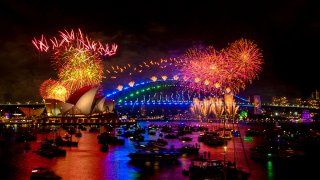 Fireworks explode over the Sydney Harbour Bridge and Sydney Opera House (L) during New Year's Eve celebrations