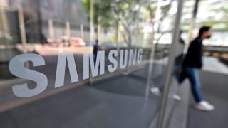 A man walks past the Samsung logo displayed on a glass door at the company’s Seocho building in Seoul on April 7, 2023.