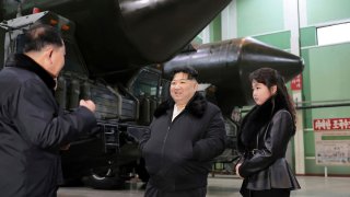 Kim Jong Un, center, with his daughter visits a factory that produces transport erector launchers in North Korea.