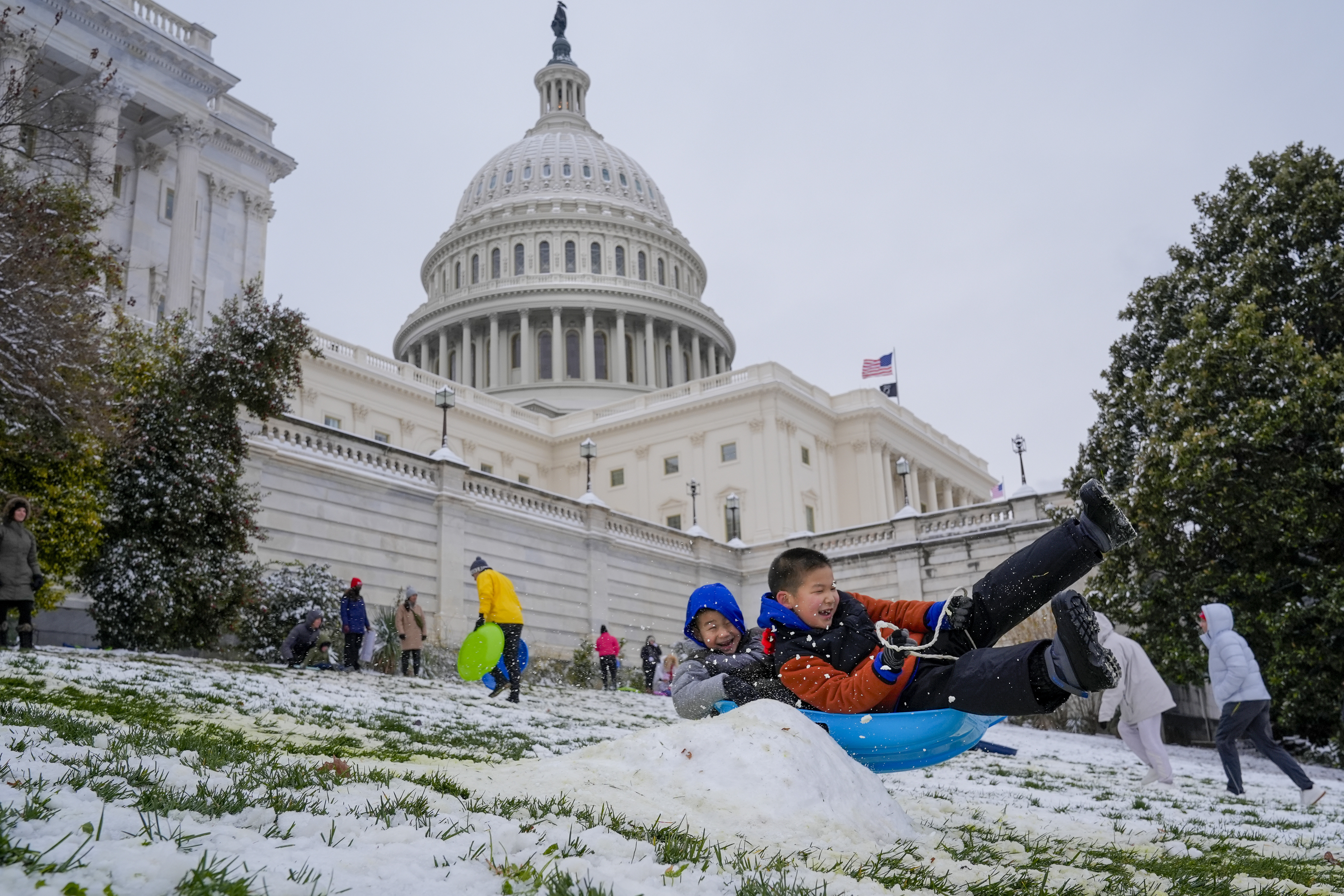 Children sled over a bump in the snow down the hill at the U.S. Capitol, as schools are closed due to a winter snowstorm, Tuesday, Jan. 16, 2024.