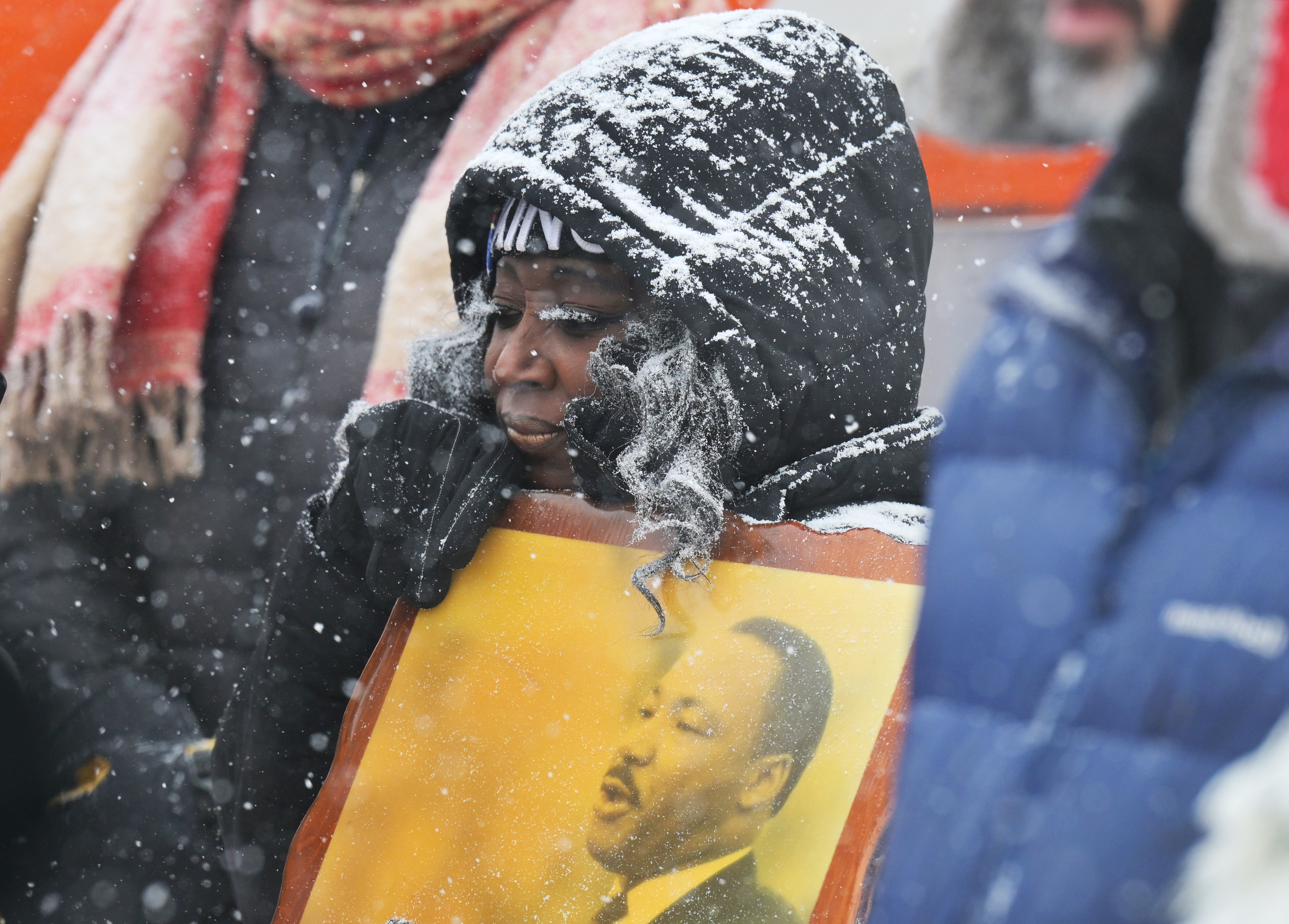 Bridget Johnson is covered in falling snow as she joined others in freezing temperatures at the annual parade celebrating the life of Dr. Martin Luther King Jr. in Denver, Colorado on Jan. 15, 2024.