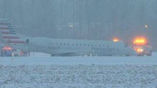 Airplane surrounded by emergency crews in snowy conditions