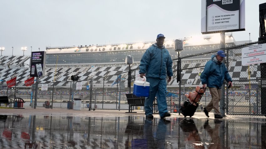 Track workers leave pit road after a NASCAR Xfinity auto race was postponed because of rain at Daytona International Speedway