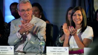 New Jersey Gov. Phil Murphy, left, and first lady Tammy Murphy seated at a table, clapping.