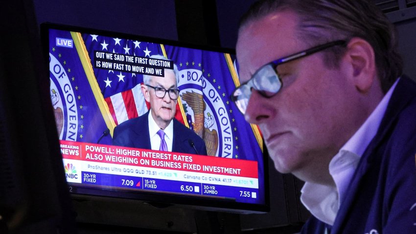 A trader works, as a screen displays a news conference by Federal Reserve Board Chair Jerome Powell following the Fed rate announcement, on the floor of the New York Stock Exchange on Dec. 13, 2023.