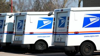 FILE – U.S. Postal Service trucks park outside a post office, Jan. 29, 2024, in Wheeling, Ill.