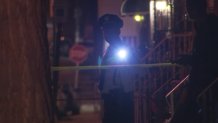 A Philadelphia Police officer investigates the scene of a shooting along the 2200 block of Sydenham Street on Wednesday night.