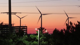 The sun sets behind spinning land-based wind turbines in Atlantic City, N.J., on Dec. 13, 2023.