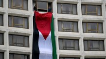 Demonstrators hang a Palestinian flag out a window at the Washington Hilton hotel during a protest over the Israel-Hamas war