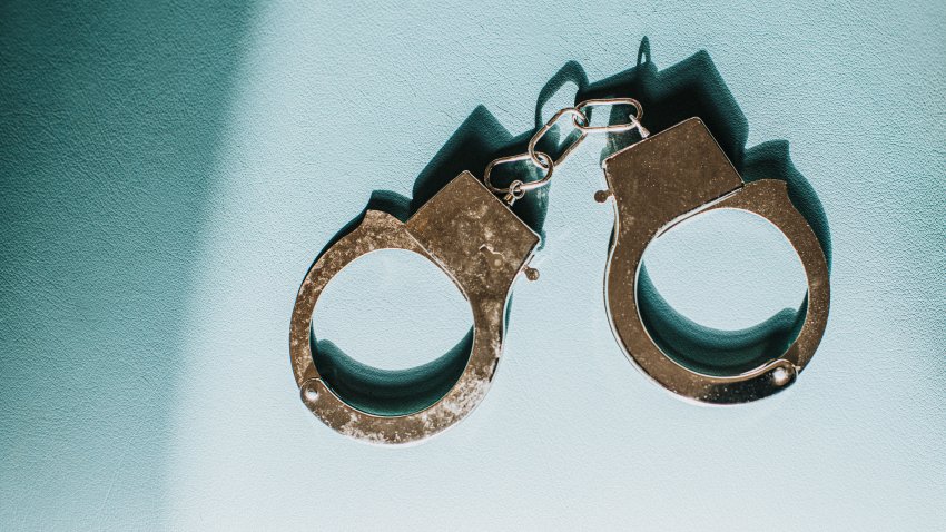 Shiny silver metal handcuffs on blue surface with space for copy.