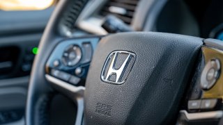 Close-up of Honda logo on steering wheel of a vehicle, with vehicle interior visible
