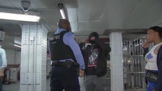 A man wearing a ski mask is questioned by transit police in Philadelphia.
