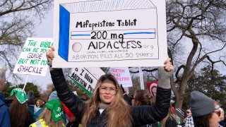 FILE – Abortion-rights activists holds a signs as they protest outside of the Supreme Court during a rally, March 26, 2024, in Washington.