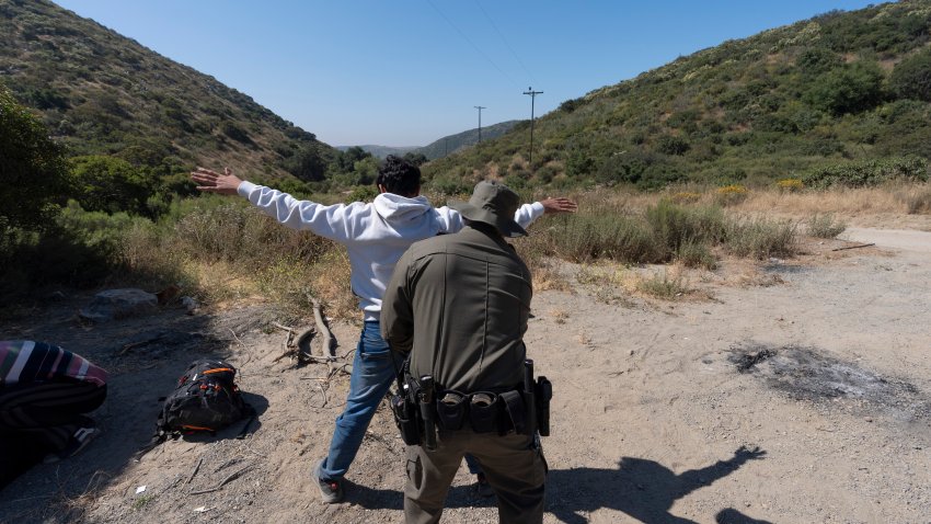 A Border Patrol agent checks a migrant seeking asylum before the man is transported and processed, Wednesday, June 5, 2024, near Dulzura, Calif. President Joe Biden on Tuesday unveiled plans to enact immediate significant restrictions on migrants seeking asylum at the U.S.-Mexico border as the White House tries to neutralize immigration as a political liability ahead of the November elections.