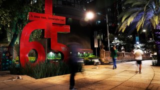 FILE – Pedestrians walk by a sculpture of a bright red number 65 that pays homage to the coal miners killed in the 2006 Pasta de Conchos mine accident, in Mexico City.