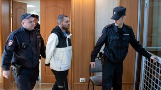 U.S. Army Staff Sgt. Gordon Black, center, is escorted into a glass cage at a courtroom in Vladivostok, Russia.