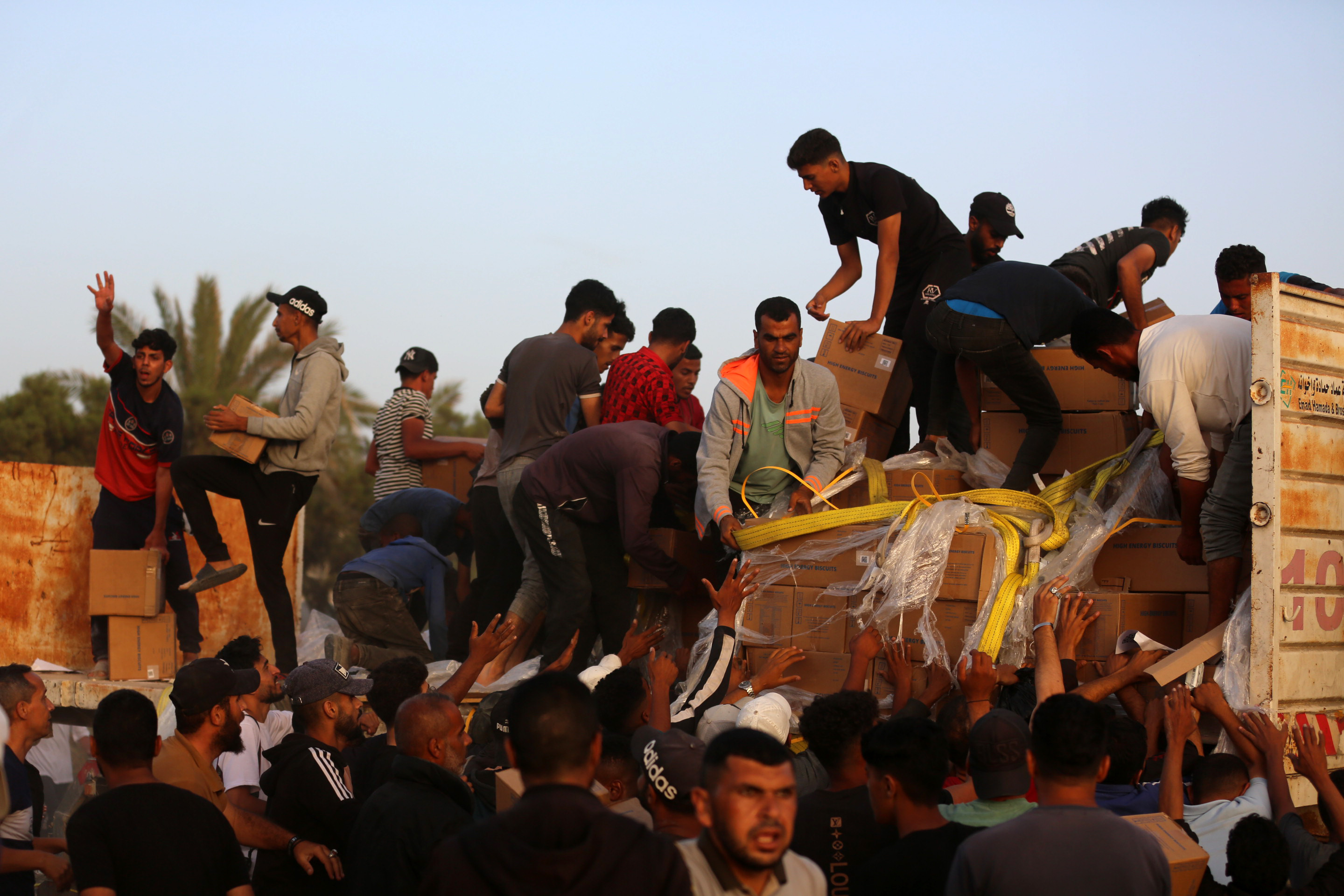 Palestinians climbing onto trucks to grab aid delivered