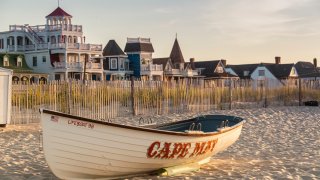 Victorian Homes and hotels line Beach Ave. in Cape May with lifesaving rescue boat on the beach.